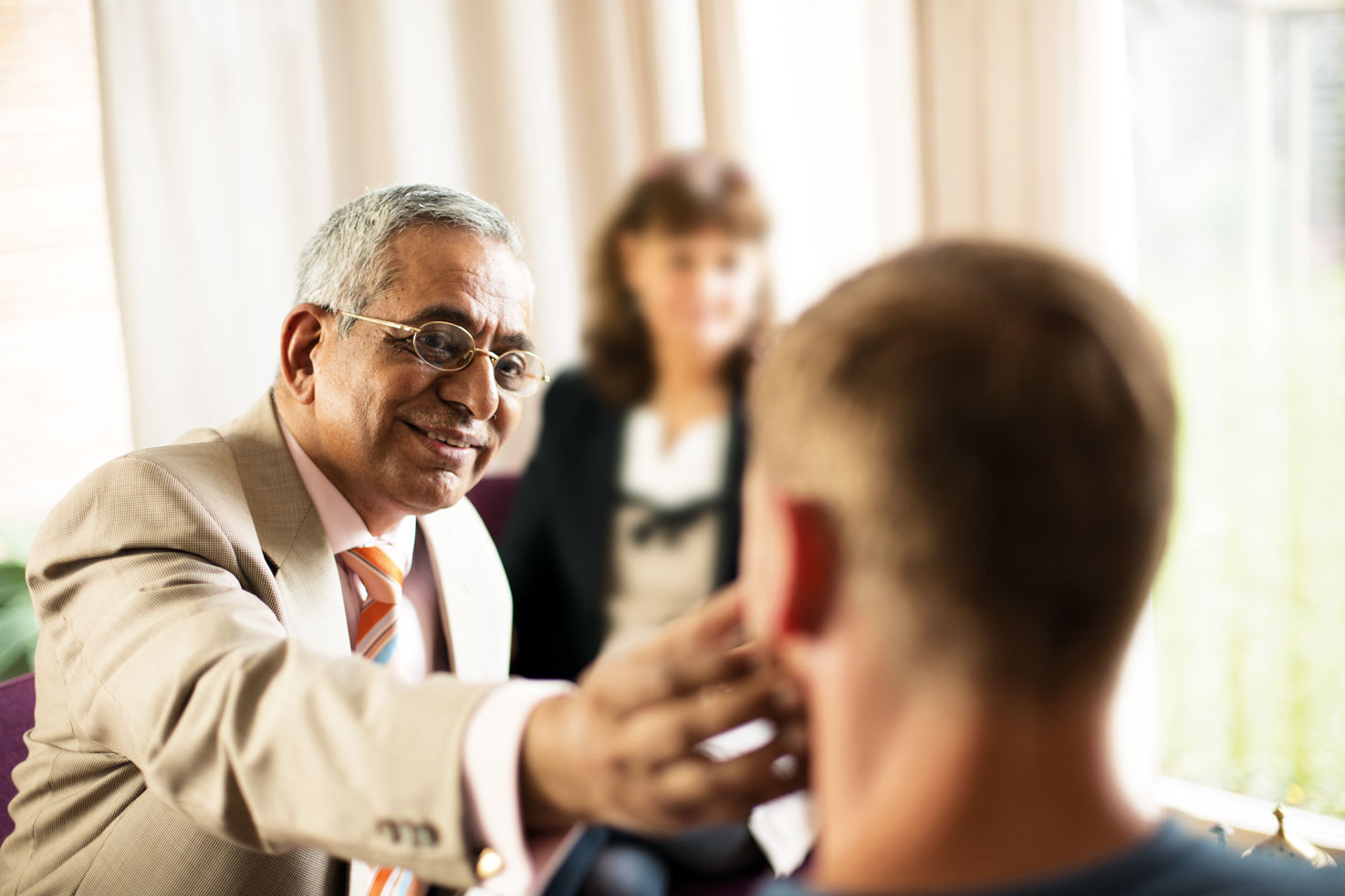 Ayurveda-Arzt untersucht einen Patienten, eine Kollegin beobachtet die Untersuchung