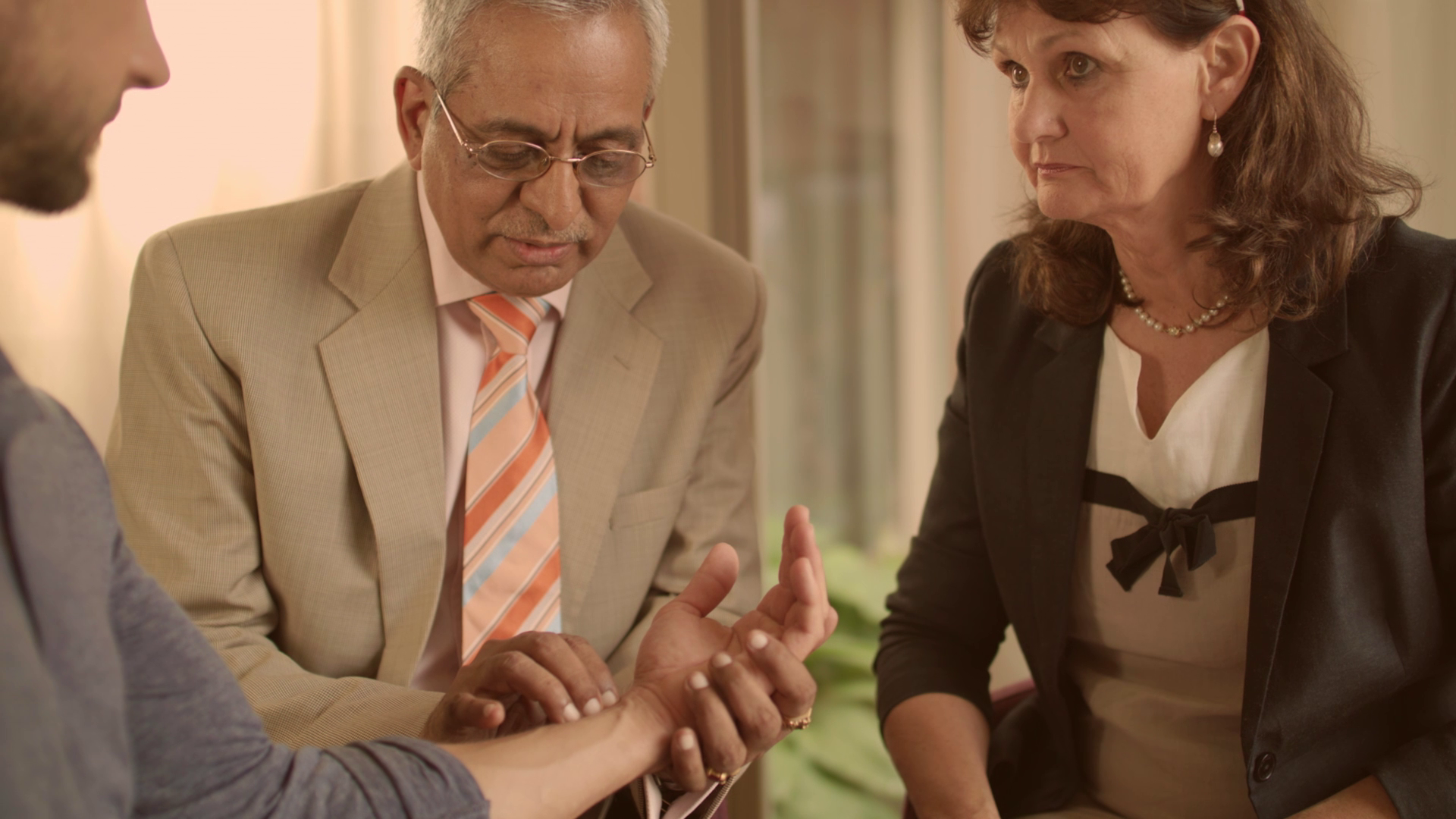Ayurveda-Arzt untersucht einen Patienten, eine Kollegin beobachtet die Untersuchung