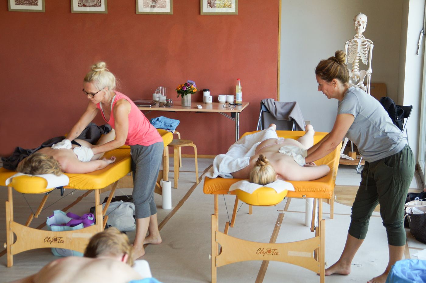 Teilnehmerinnen üben die Abhyanga an Massageliegen im Seminarraum